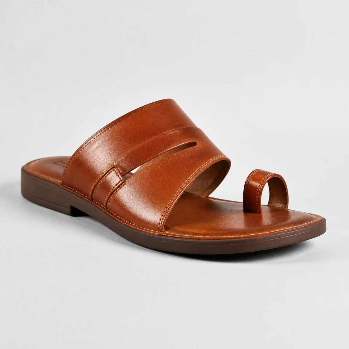Une sandale plate marron en cuir pour homme avec une bride d'orteil et des lanières larges sur le dessus, présentée en studio sur un fond neutre.   